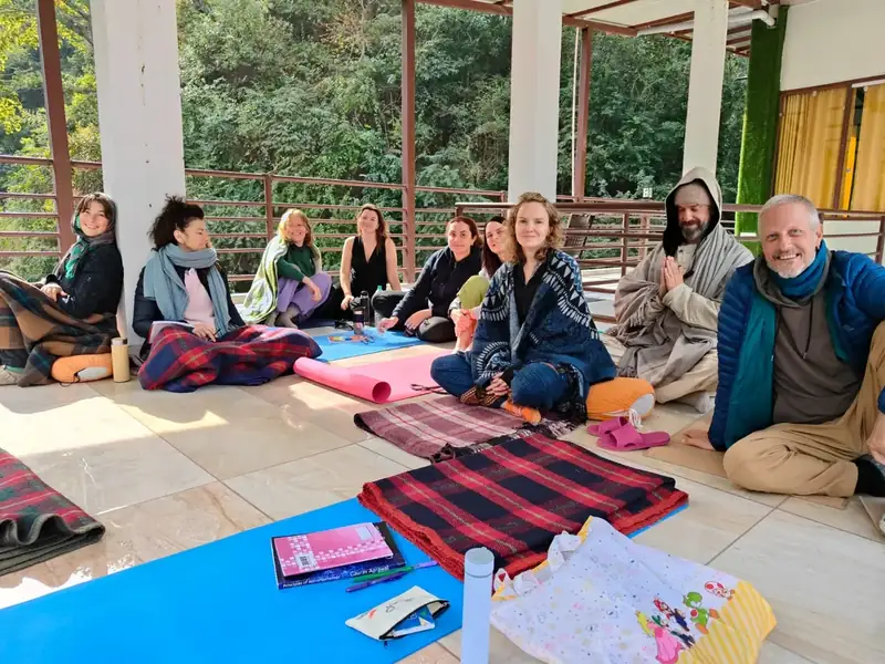 Students sitting together for an outdoor class on the terrace at Sri Yoga Ashram, Rishikesh
