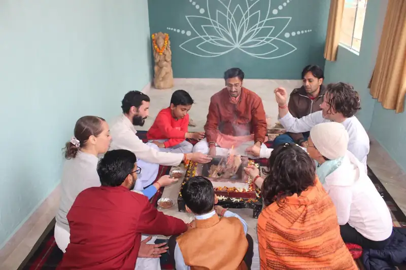Traditional havan fire ceremony with students and priests seated around the fire in Rishikesh