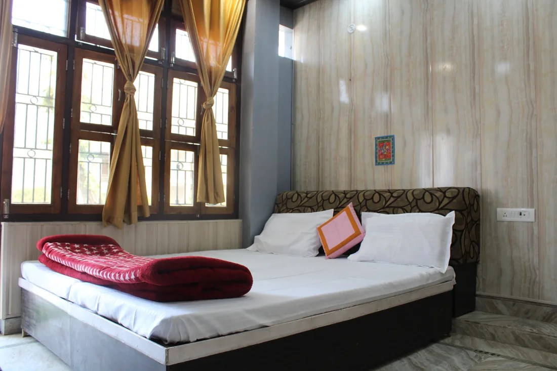 Bright guest room with double bed and daylight windows at Sri Yoga Ashram, Rishikesh