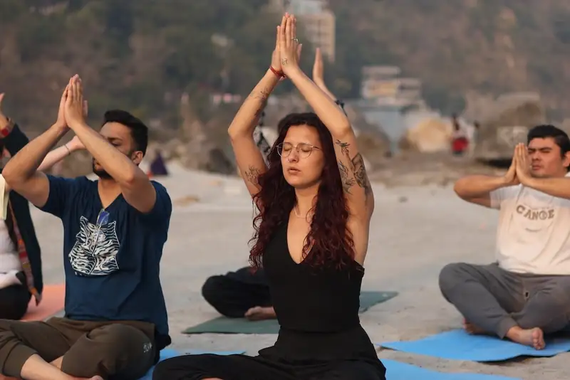Students practising yoga on the riverbank at Sri Yoga Ashram, Rishikesh